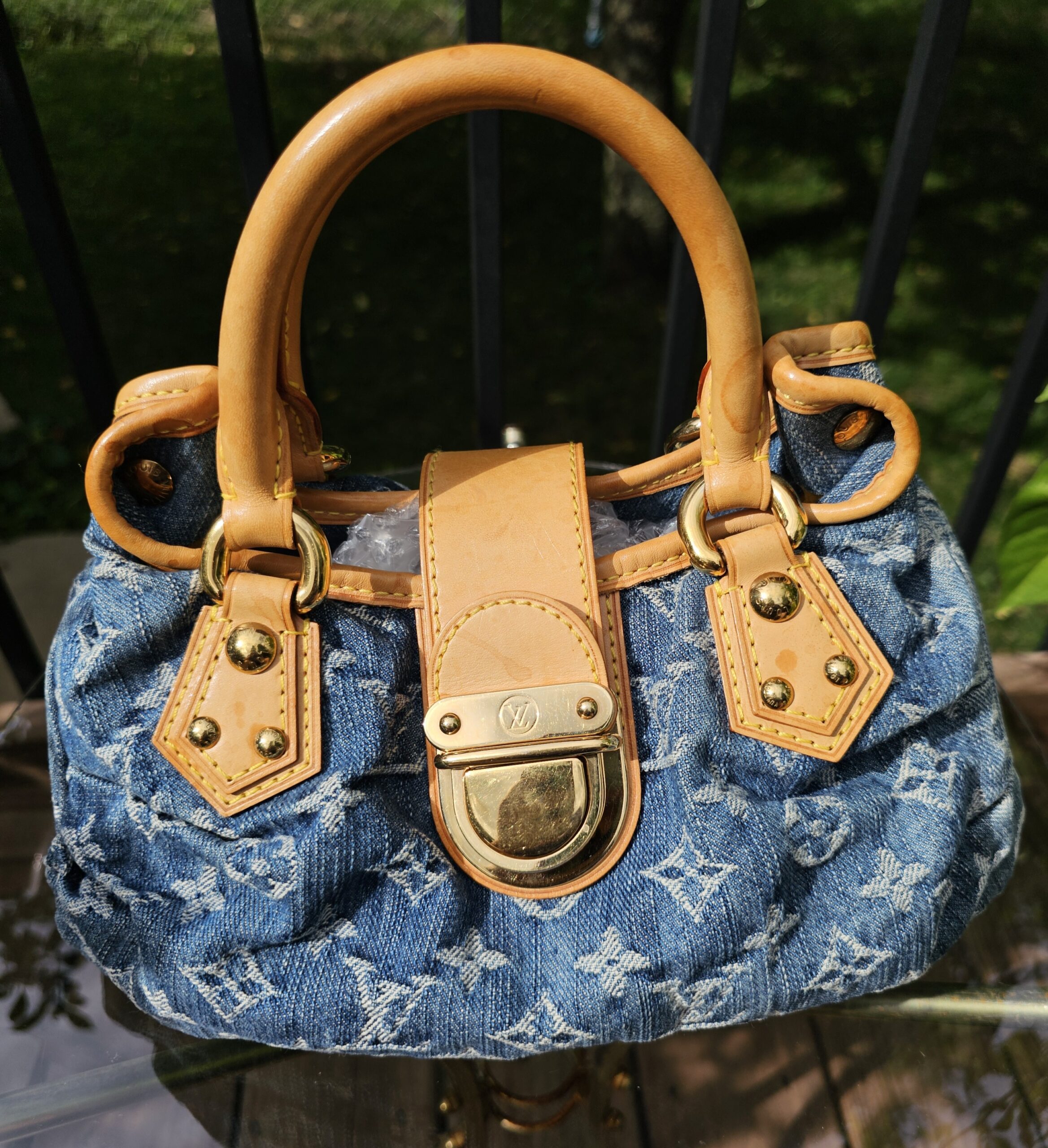 Louis Vuitton Monogram Denim Pleaty Blue - front view with the gold-tone push lock and vachetta trim