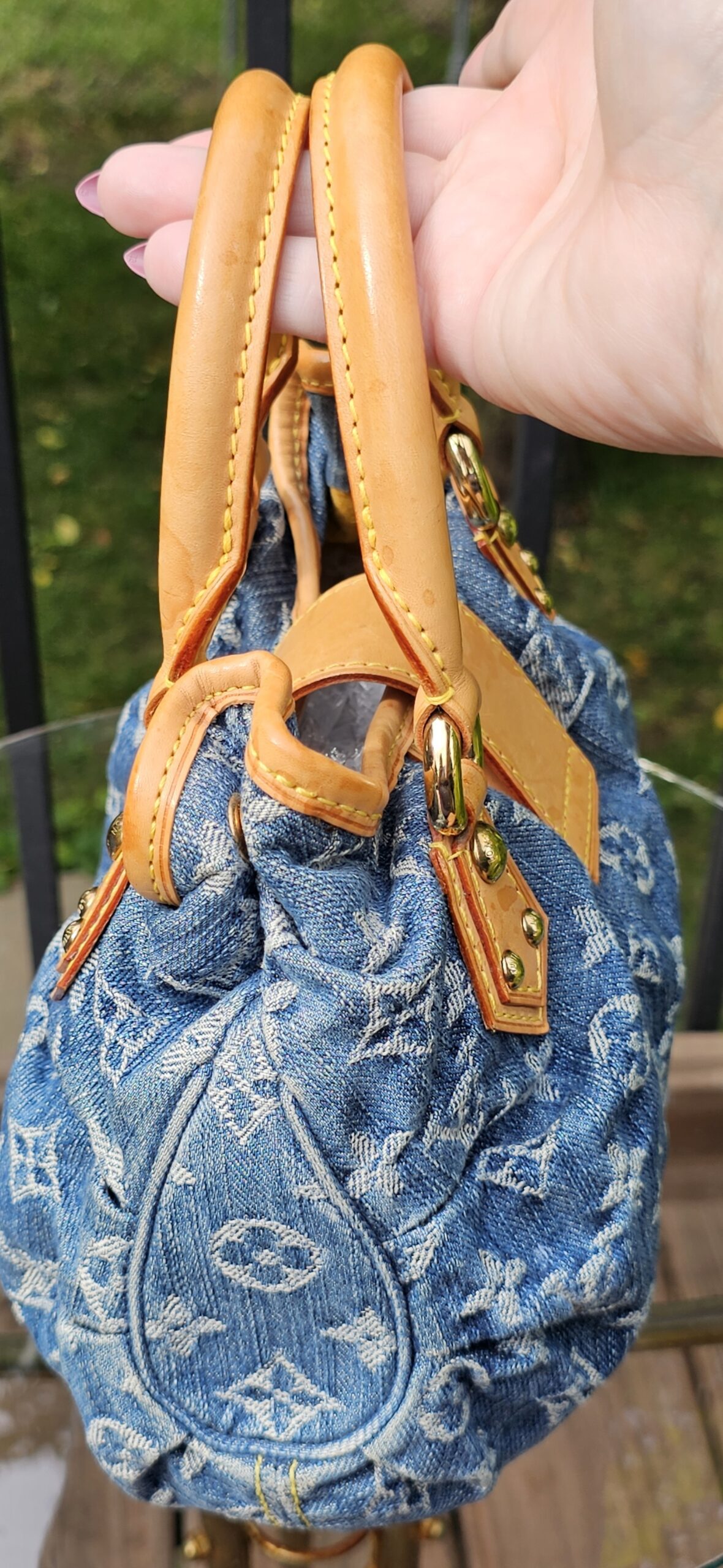 Blue Monogram Denim Pleaty held by its handles
