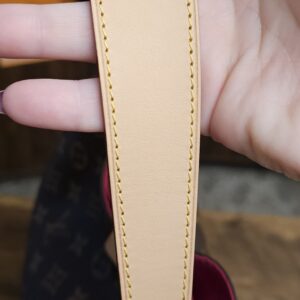 Light vachetta shoulder strap held in hand