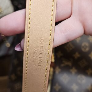 Light vachetta shoulder strap held in hand