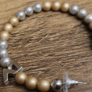 Alternating gold-tone, silver and marbled faux pearl beads with the LV charm
