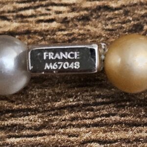 Small silver tag stamped FRANCE and M67048 between the beads