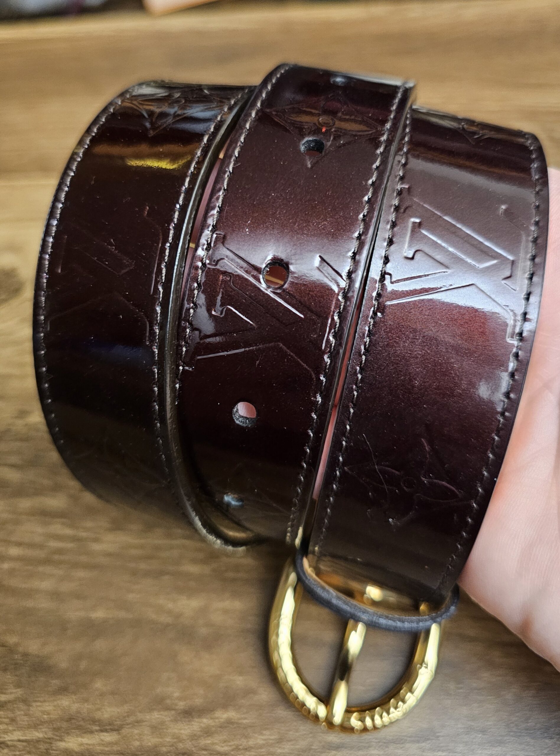 Embossed Monogram in the Amarante Vernis held in hand
