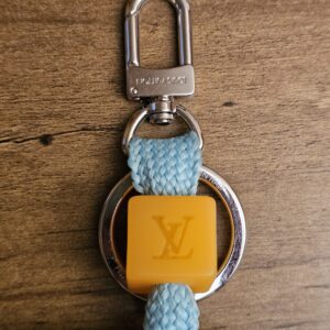 Silver-tone clasp and orange LV cube on the light blue braided cord