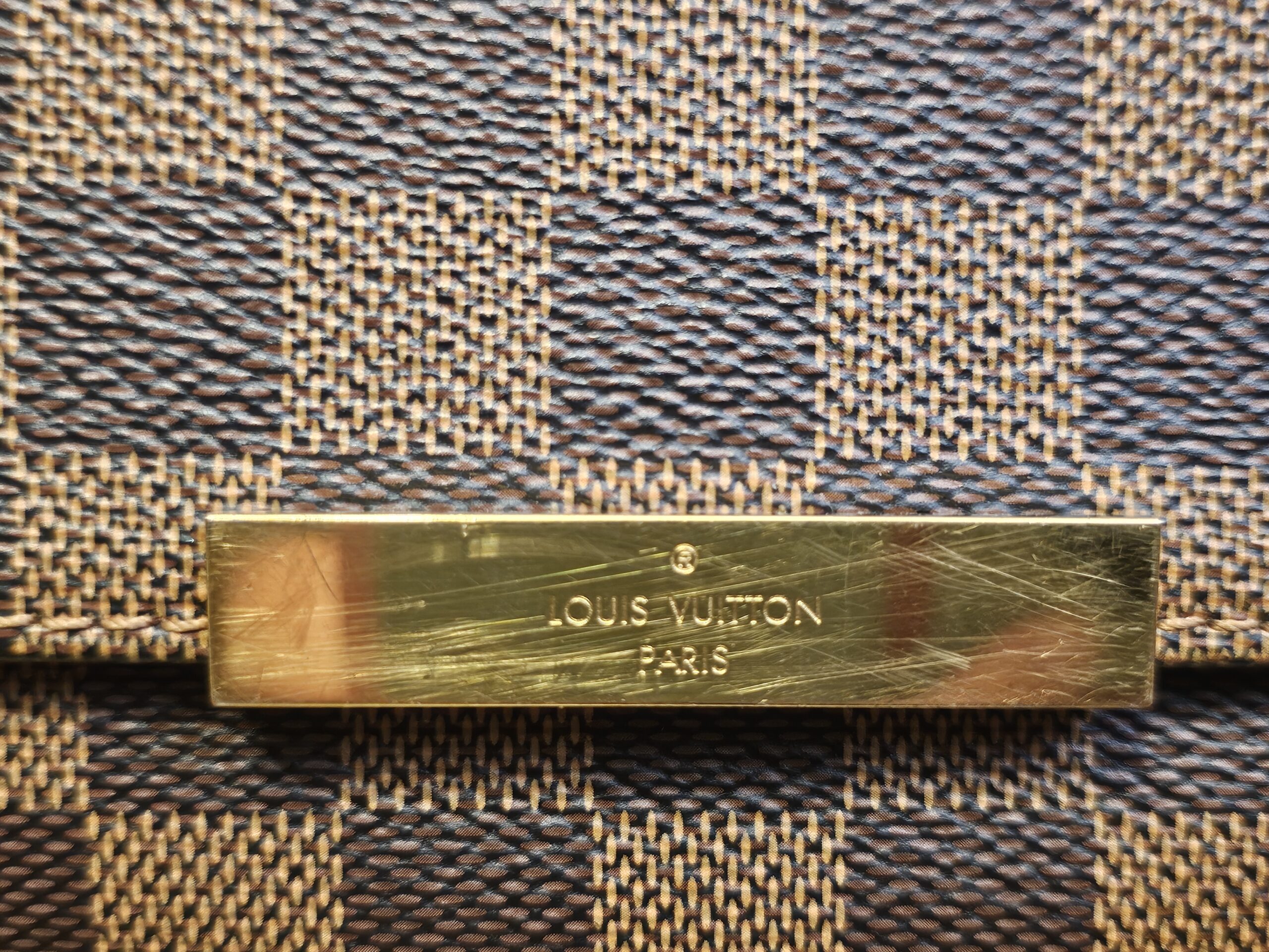 Gold-tone plate engraved LOUIS VUITTON PARIS, showing scratches