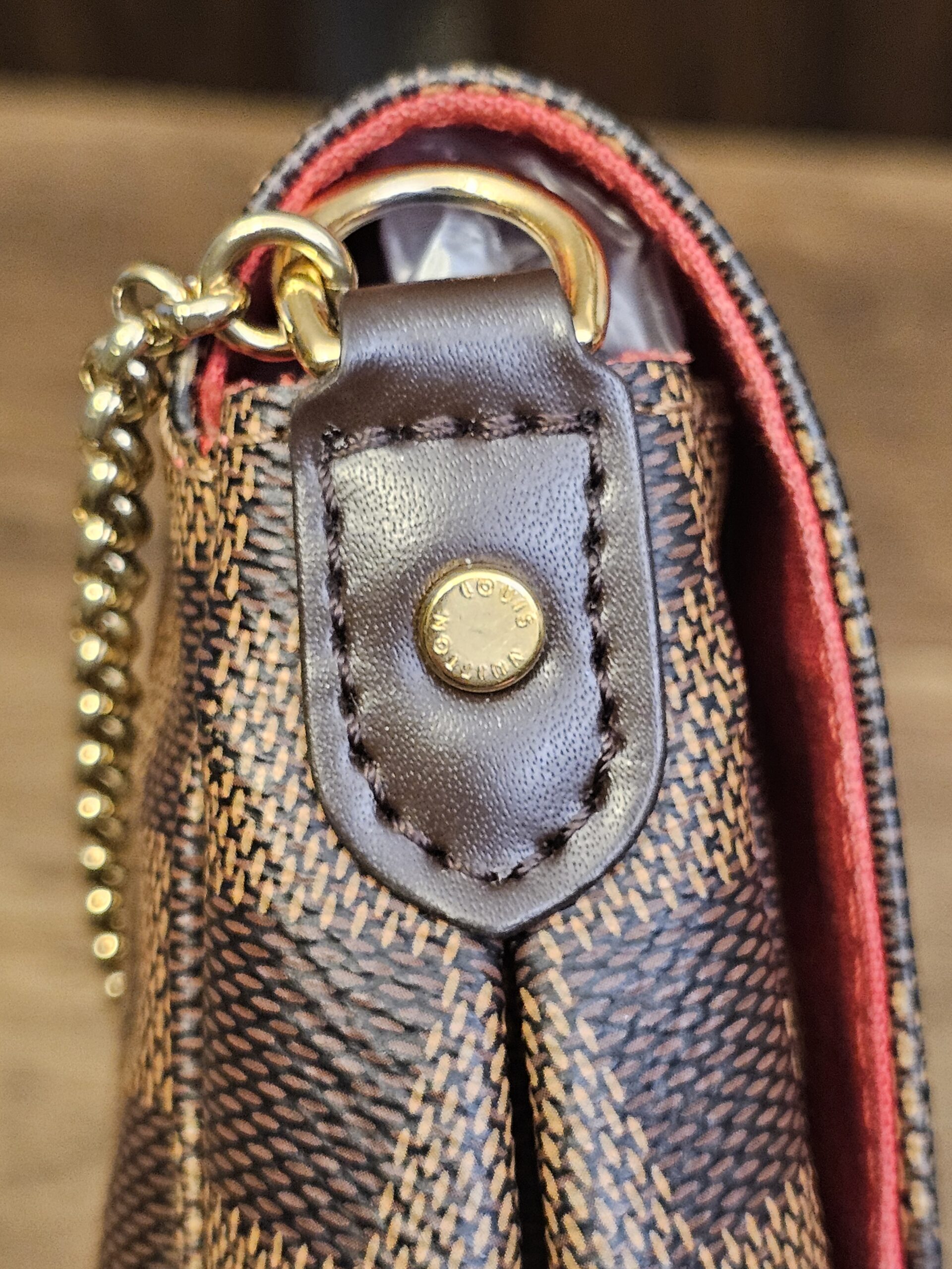 Brown leather tab and gold-tone D-ring on the side of the bag