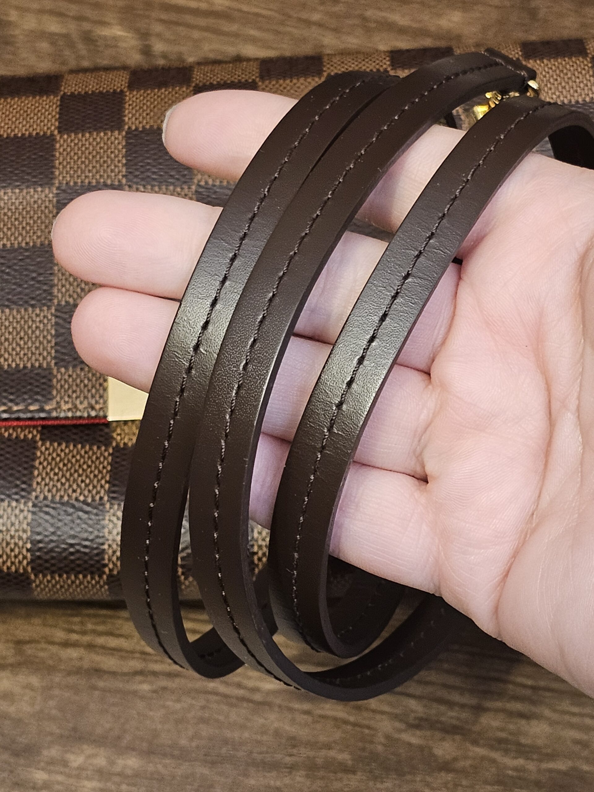 Removable brown leather strap held in hand