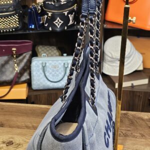 Side of the denim Deauville tote showing the gusset and the chain shoulder straps