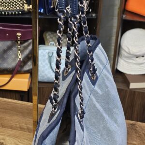 Angled view of the blue denim tote with the shoulder straps gathered together