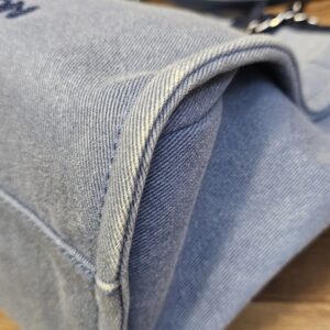 Top corner of the washed denim tote showing the folded gusset