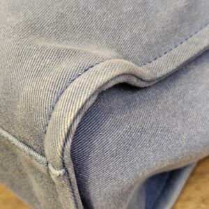 Bottom corner of the denim tote showing the seam and light fading
