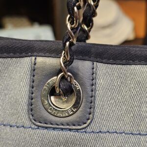 Grommet stamped CHANEL where the chain strap meets the denim body