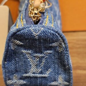 Blue Monogram denim pouch standing upright with the gold-tone chain attached