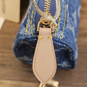 Gold-tone zip and natural cowhide leather pull on the denim pouch