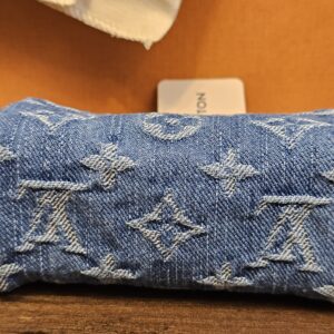 Blue Monogram denim Speedy Trousse laid flat in front of the Louis Vuitton box