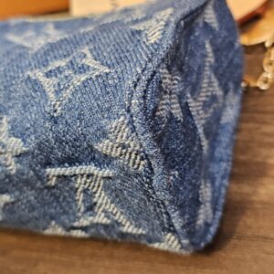 Angled view of the denim pouch with the gold-tone chain and original tags