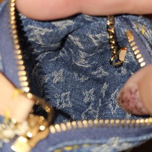 Zip opening of the denim pouch with the gold-tone clasp alongside