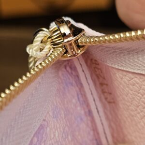 Close view of the gold-tone zip pull and chain on the key pouch
