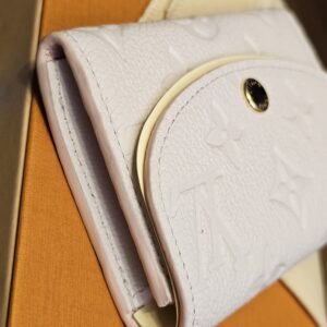 Side profile of the Rosalie coin purse resting on the Louis Vuitton box