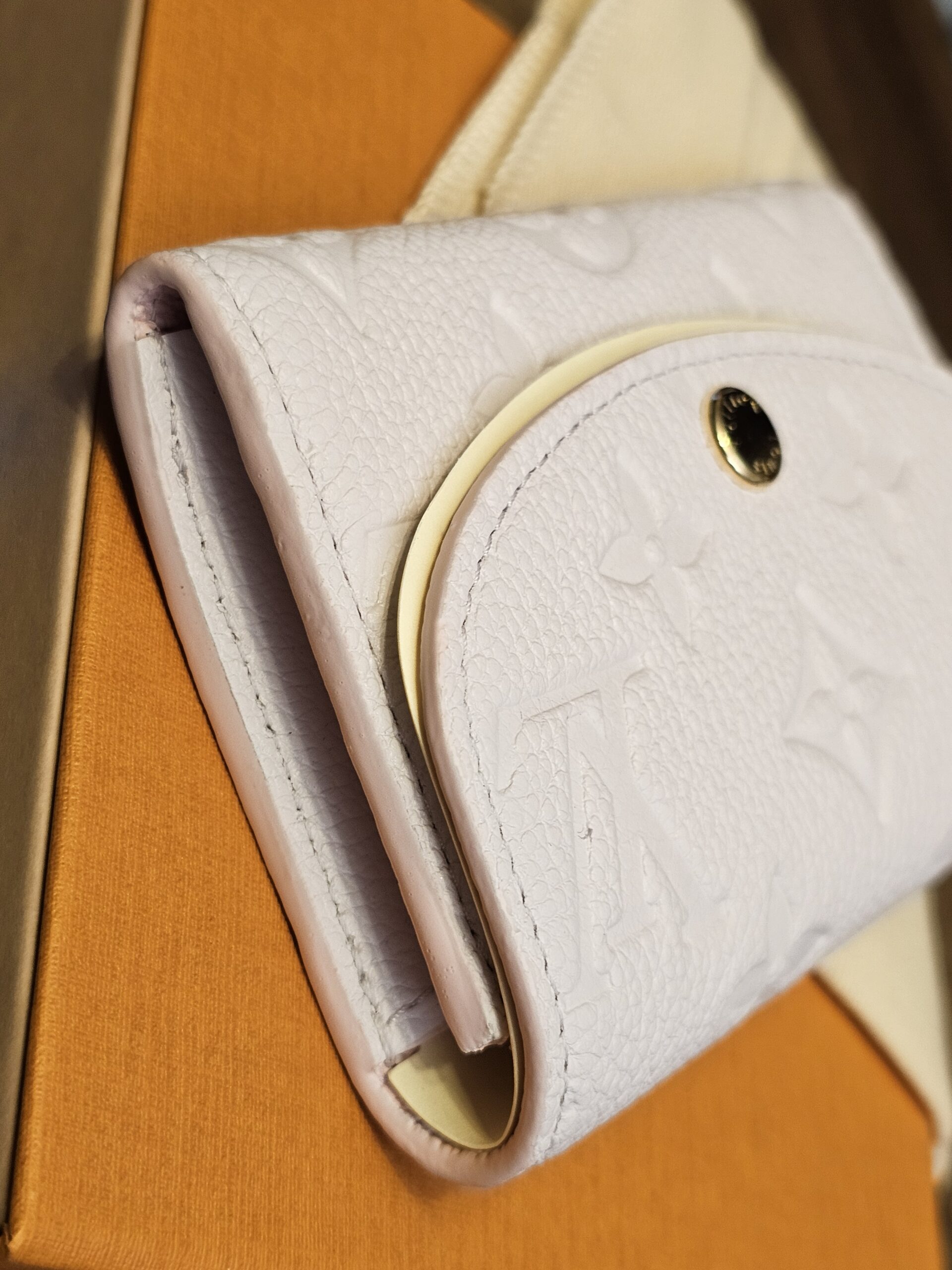 Side profile of the Rosalie coin purse resting on the Louis Vuitton box