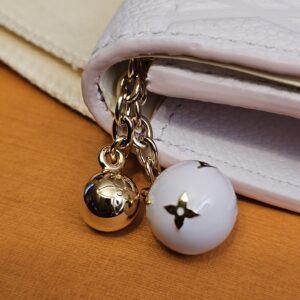Gold-tone ball and white enamel Monogram flower charms on the zip pull