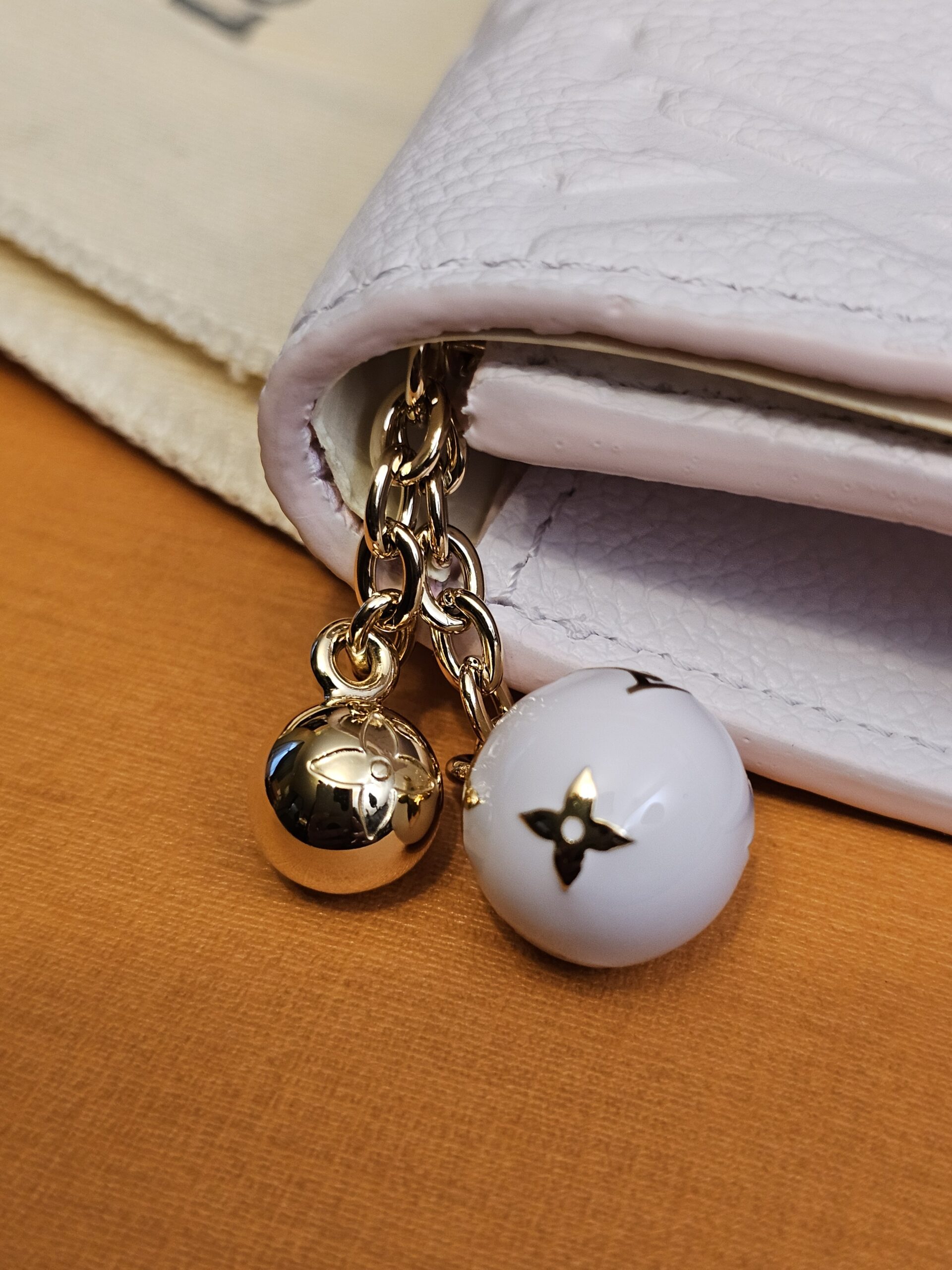 Gold-tone ball and white enamel Monogram flower charms on the zip pull