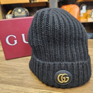 Gucci Interlocking G Ribbed Knit Beanie Black standing beside the Gucci box, showing the gold Interlocking G patch