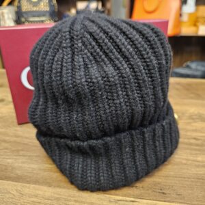 Black ribbed knit beanie seen from the side with the folded cuff