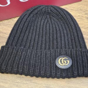 Black Gucci beanie laid in front of the red Gucci box