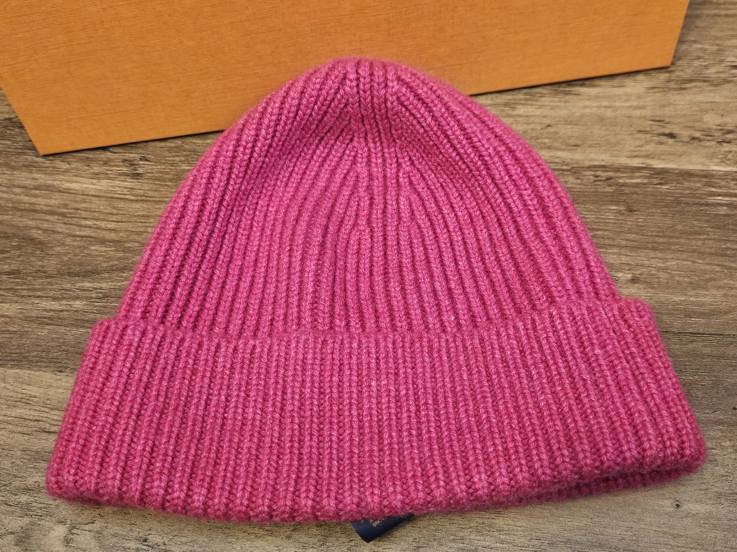 Fuchsia pink ribbed cashmere beanie laid flat on the Louis Vuitton box