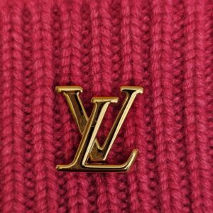 Close up of the gold tone LV logo on the fuchsia ribbed cashmere knit