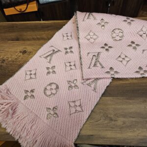 Louis Vuitton Logomania Shine Wool Scarf Pink folded on a wood table showing the metallic Monogram and fringe