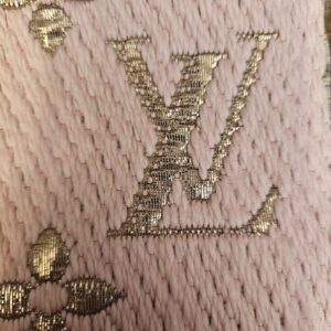 Close up of the metallic LV monogram woven into the pink scarf