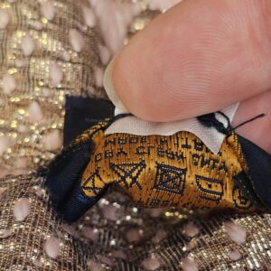 Close up of the Louis Vuitton label tucked against the metallic woven side of the scarf