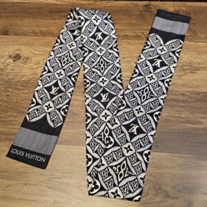 Louis Vuitton Silk Since 1854 Bandeau Black Cream Gray laid out on a wood table with the Louis Vuitton name on the end