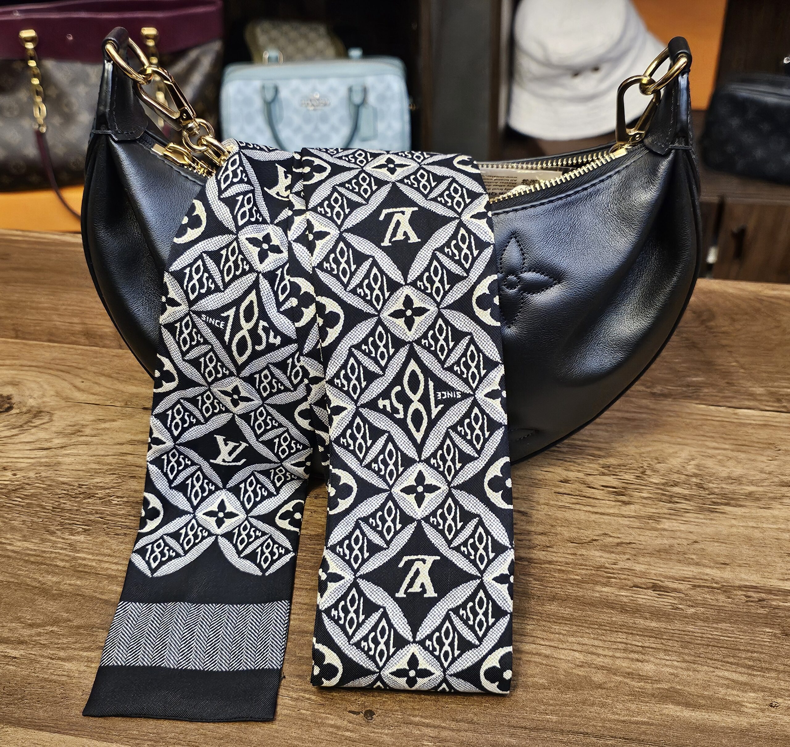 Bandeau tied around the handle of a black Louis Vuitton bag