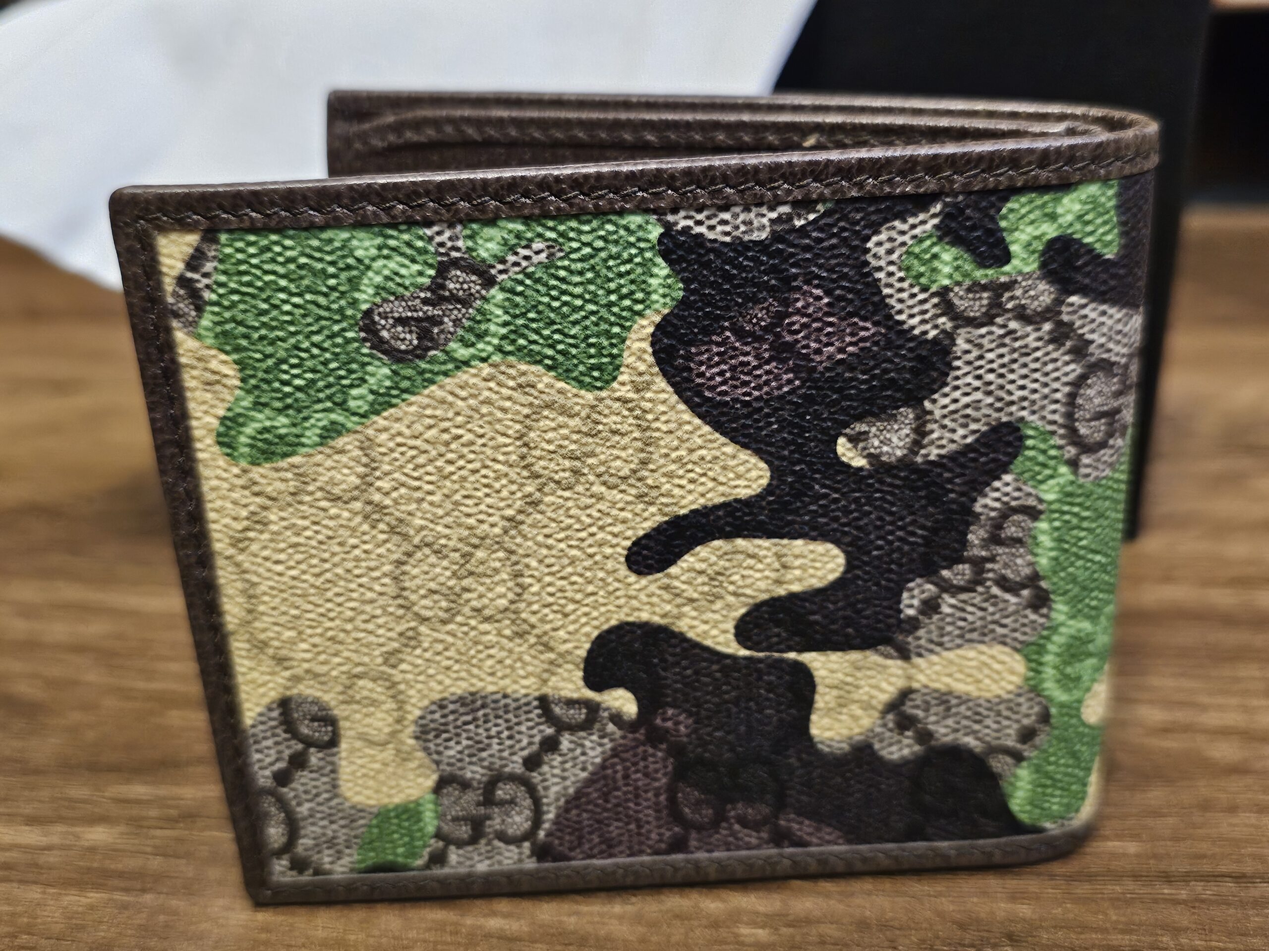 Gucci camouflage bifold wallet closed and angled on white tissue