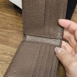 Gucci wallet opened to show the brown leather card slots and interior