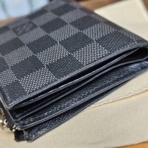 Side profile of the folded Smart Wallet resting on the Louis Vuitton dust bag