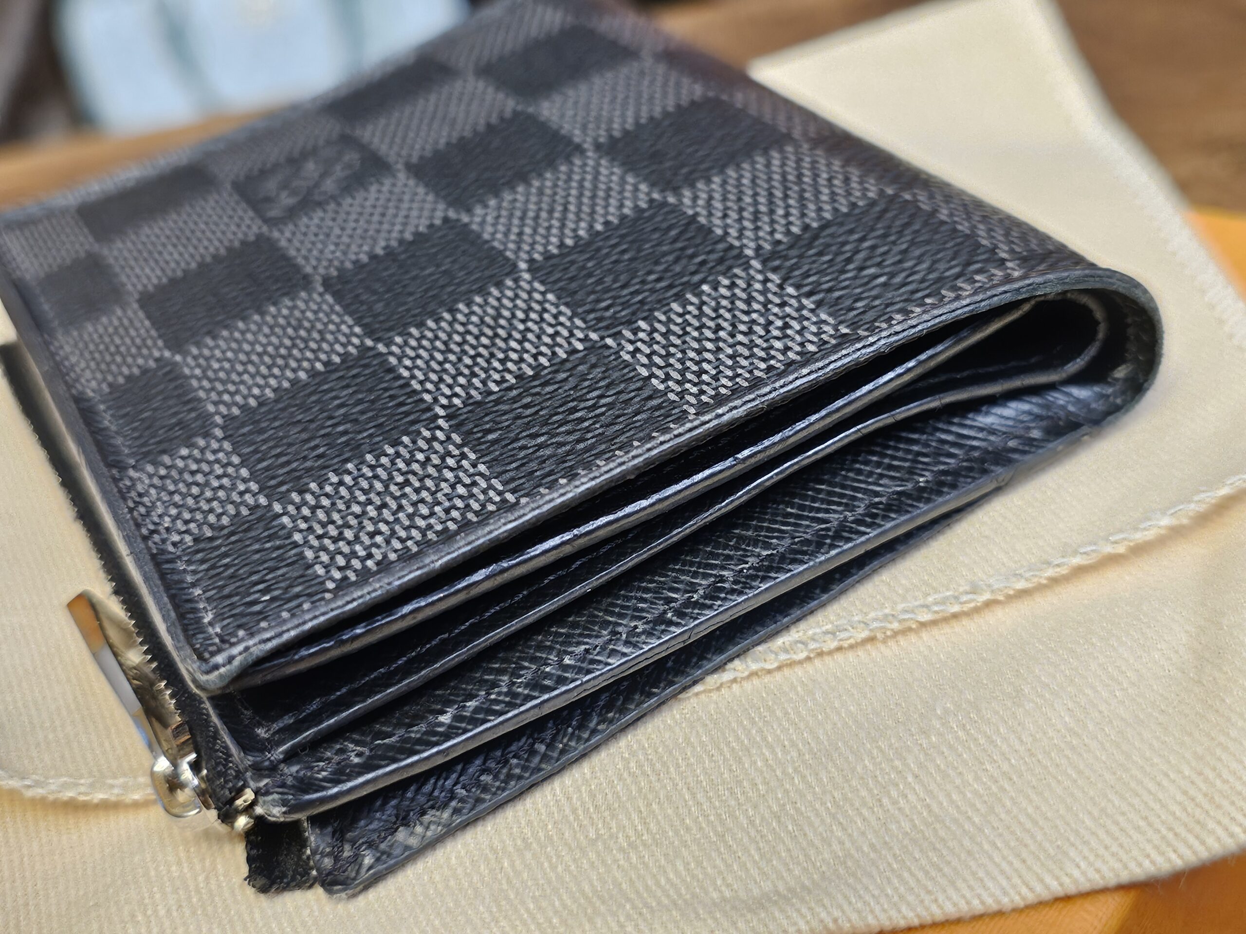 Side profile of the folded Smart Wallet resting on the Louis Vuitton dust bag