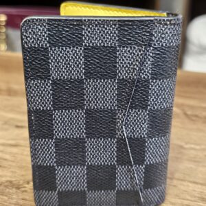 Damier Graphite pocket organizer standing closed with the bold yellow stripe