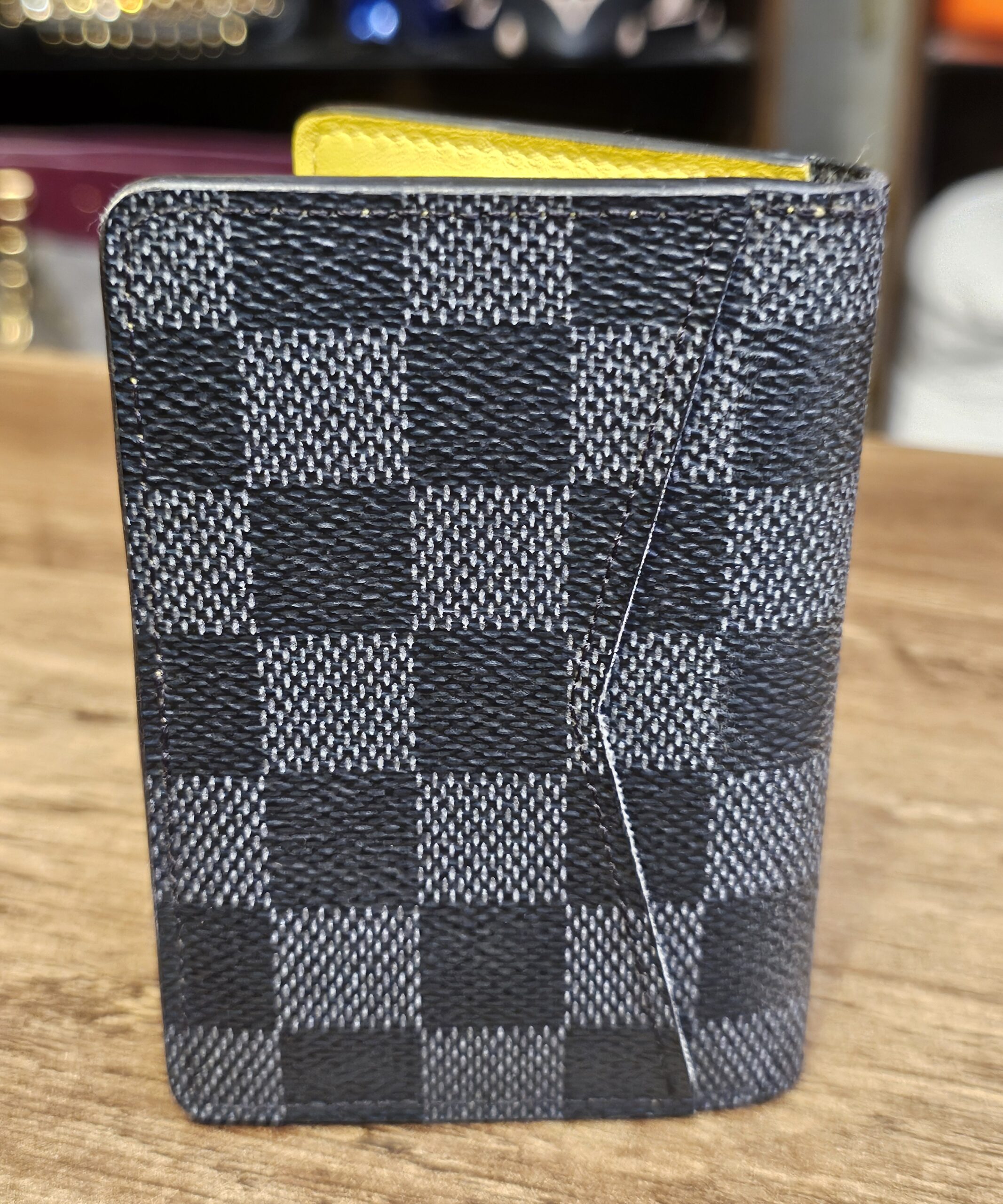 Damier Graphite pocket organizer standing closed with the bold yellow stripe