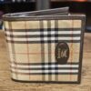 Burberrys Nova Check Bifold Wallet closed, showing the camel check canvas and the leather logo oval