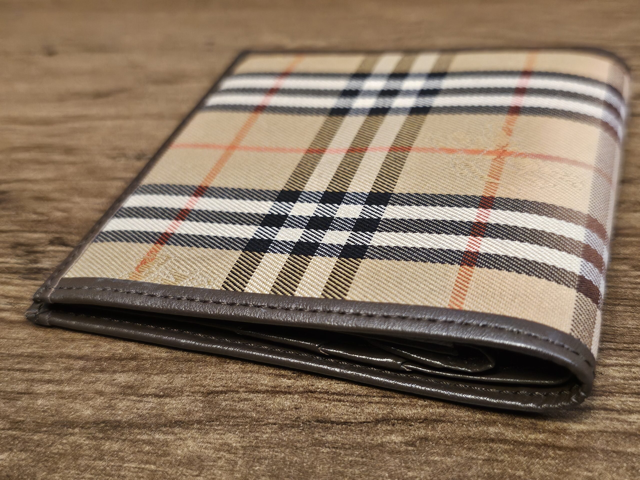 Burberrys Nova Check bifold wallet angled on a wood table