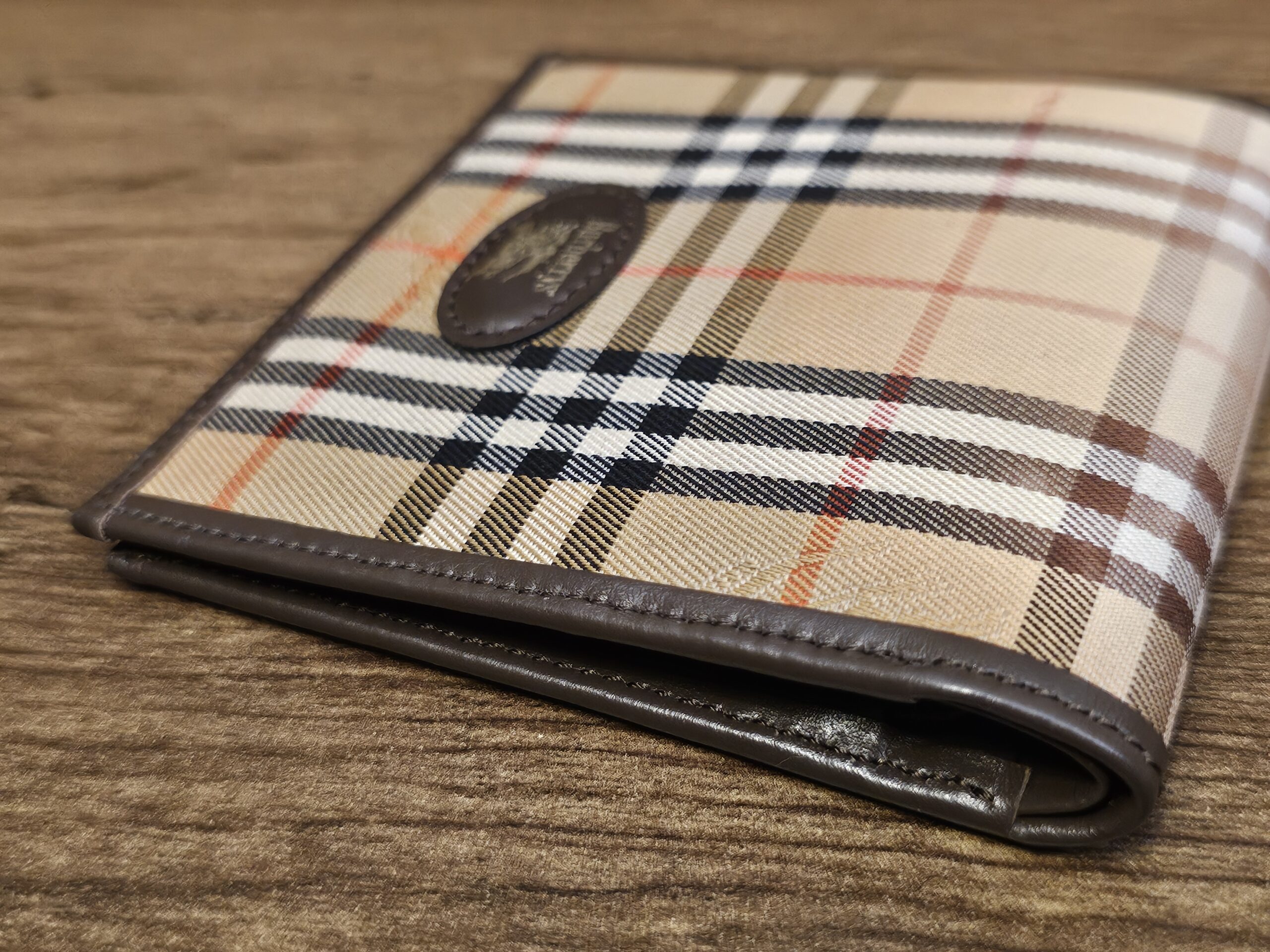 Burberrys wallet showing the camel check canvas against the dark brown leather trim
