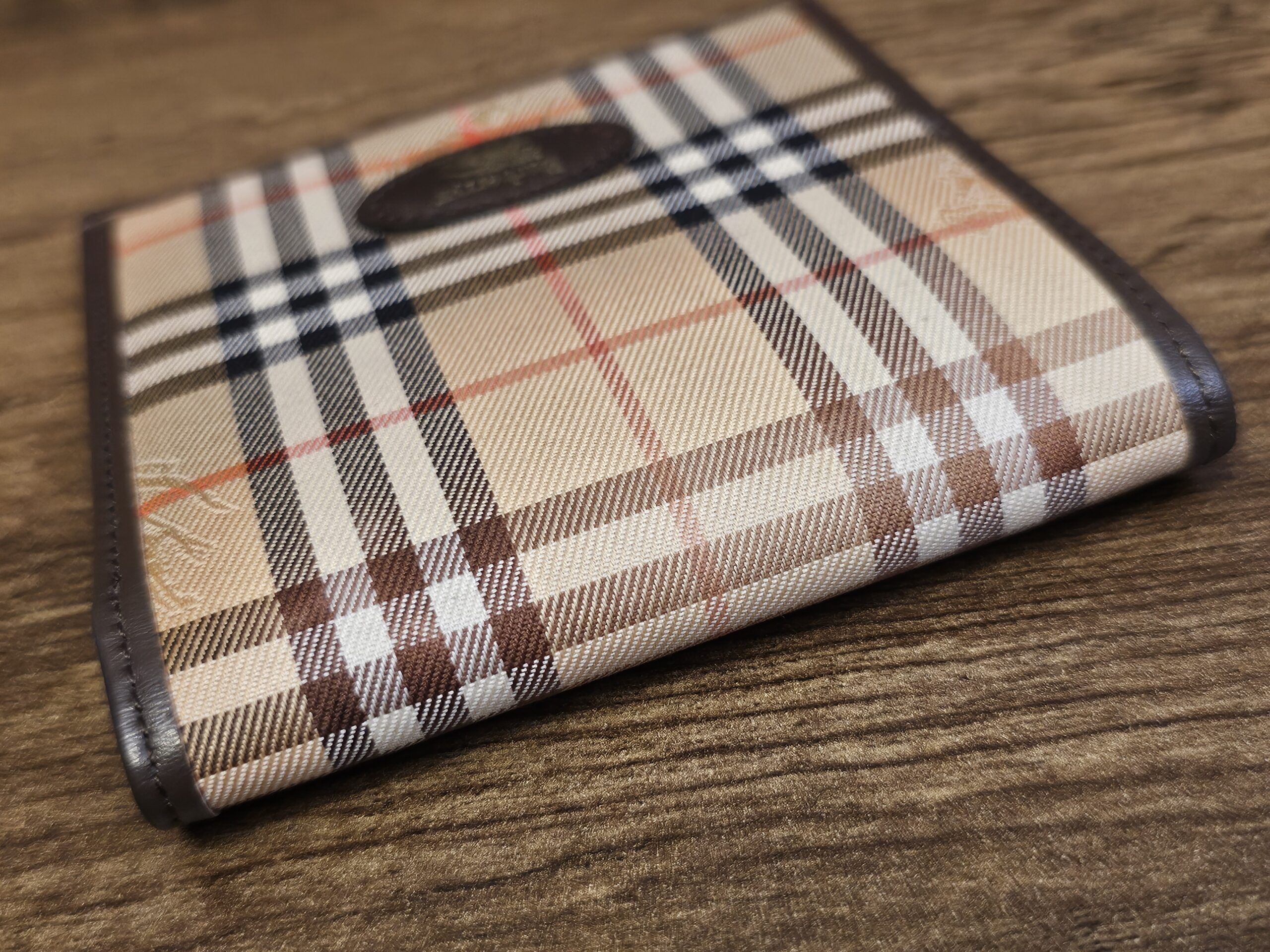 Burberrys bifold wallet standing closed with the leather logo oval in view