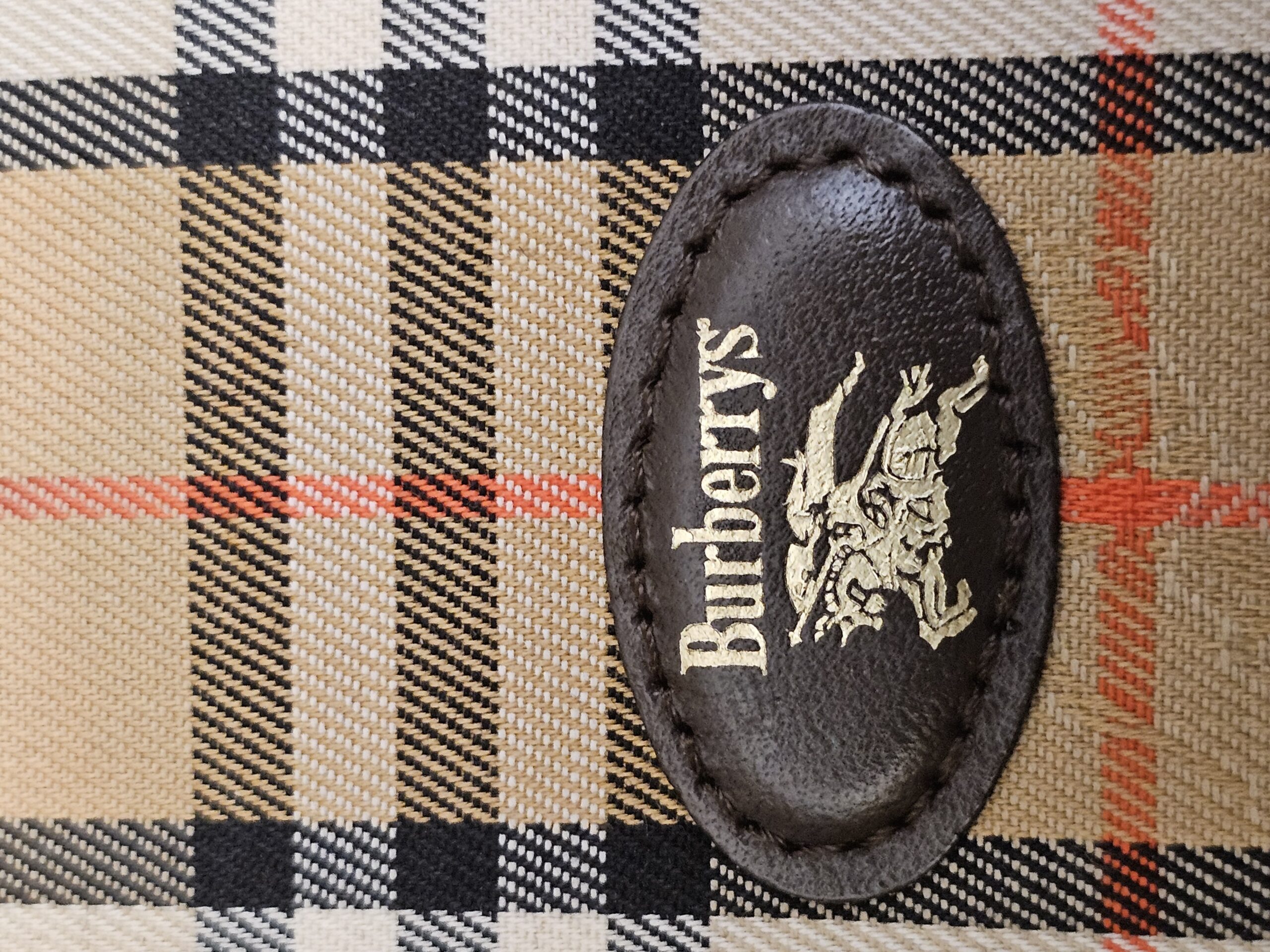 Close up of the Burberrys name and equestrian knight stamped on the leather oval