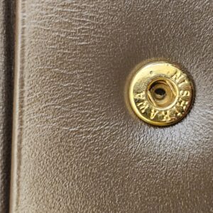 Close up of the gold-tone snap stud on the Burberrys wallet