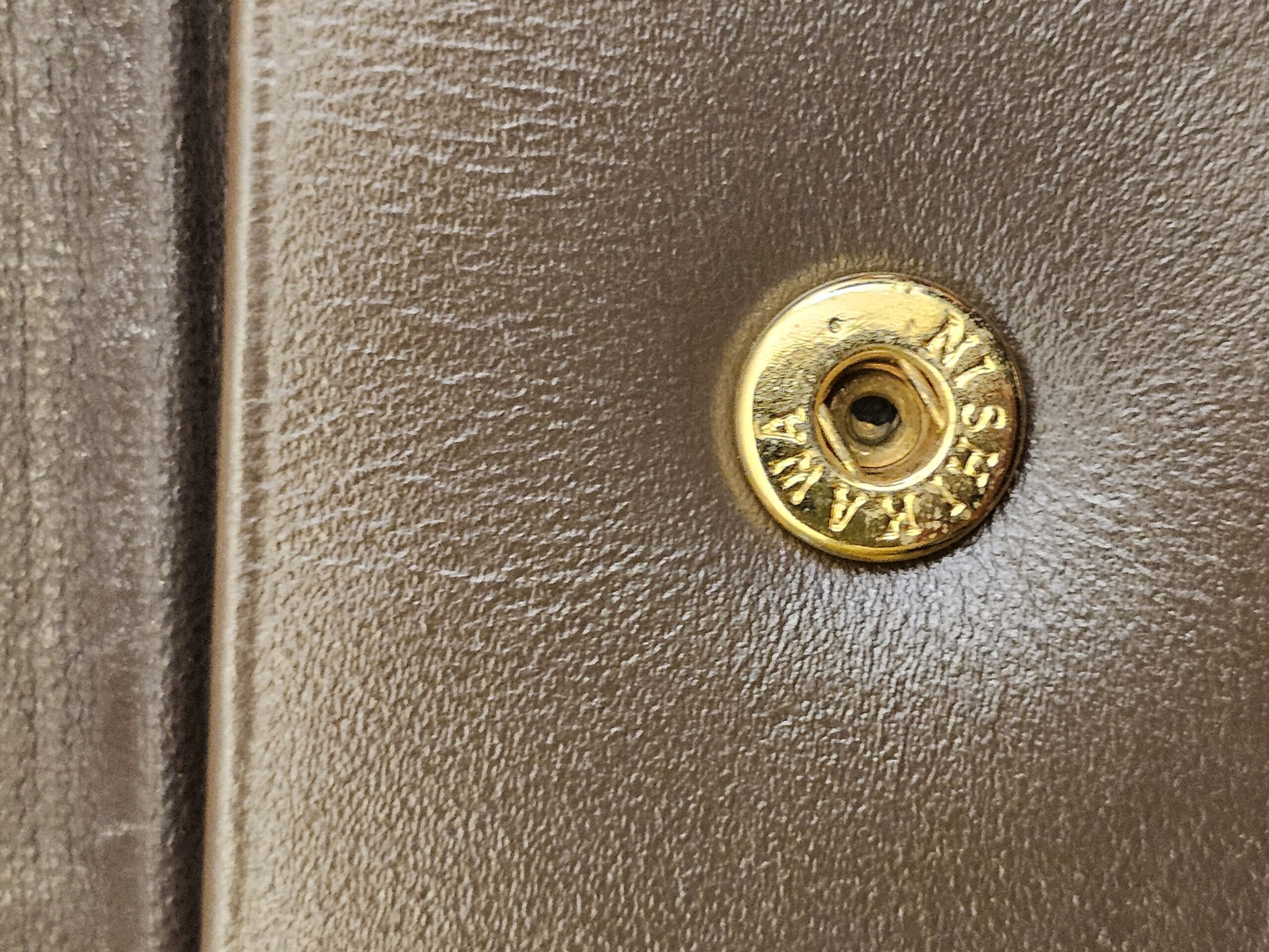 Close up of the gold-tone snap stud on the Burberrys wallet