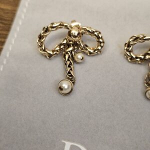 Both gold-tone Dior bow earrings angled on the Dior pouch